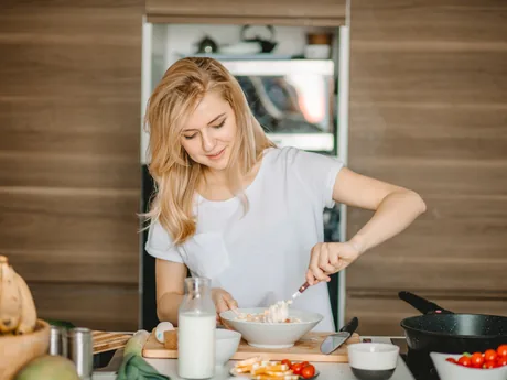 A woman preparing food at a kitchen counter with fresh ingredients