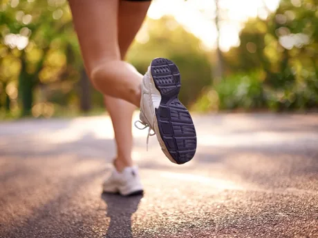 A close view of a woman's running shoes mid-stride on a path